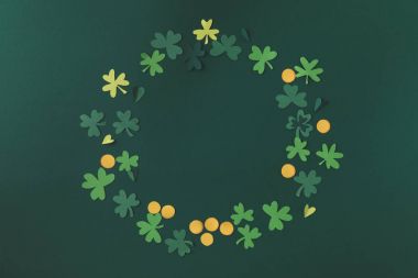 top view of paper decoration of coins and shamrock for st patricks day isolated on green clipart