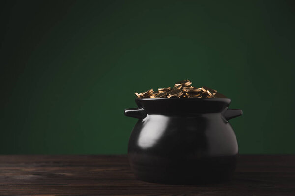 pot of golden coins on wooden table, st patricks day concept