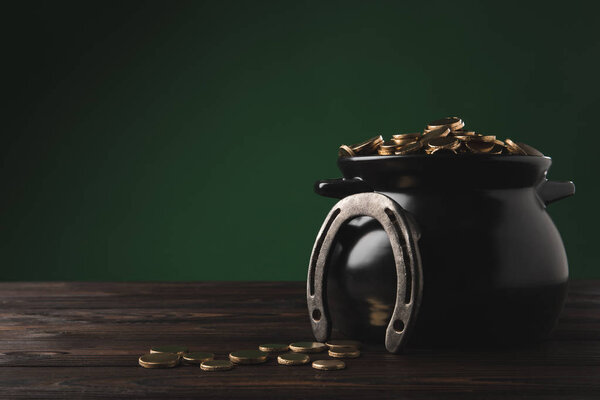 pot with golden coins and horseshoe on table, st patricks day concept