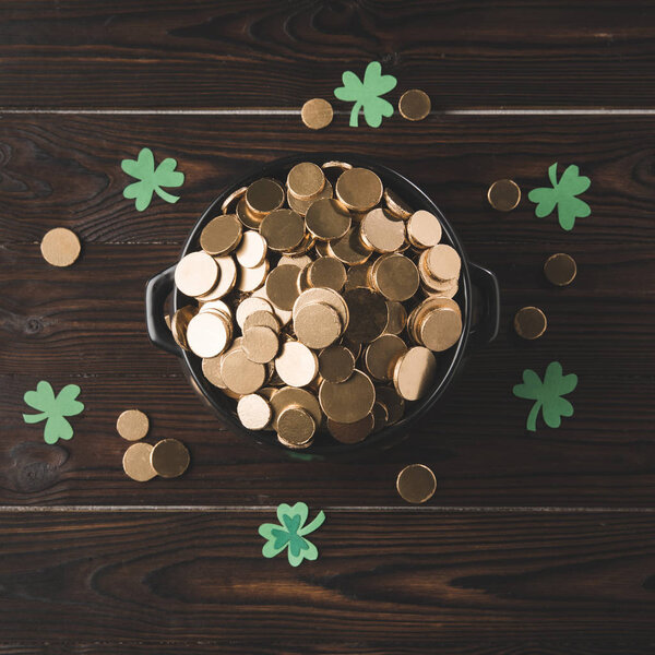 top view of pot with golden coins and shamrock on wooden table, st patricks day concept