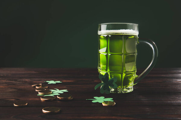 стакан пива с трилистником и золотыми монетами на деревянном столе, день святого Патрика
