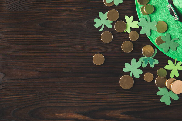 top view of green hat with golden coins and shamrock on wooden table, st patricks day concept