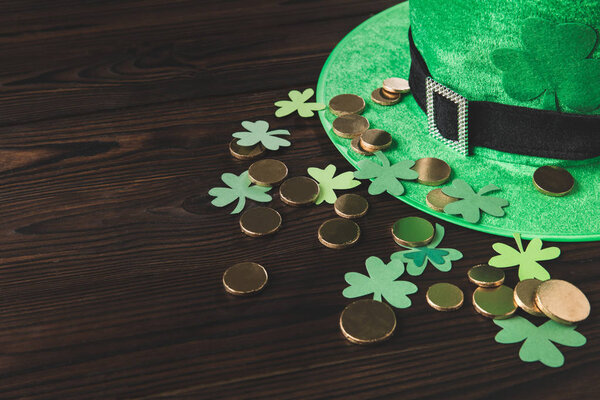 green hat with golden coins and shamrock on wooden table, st patricks day concept