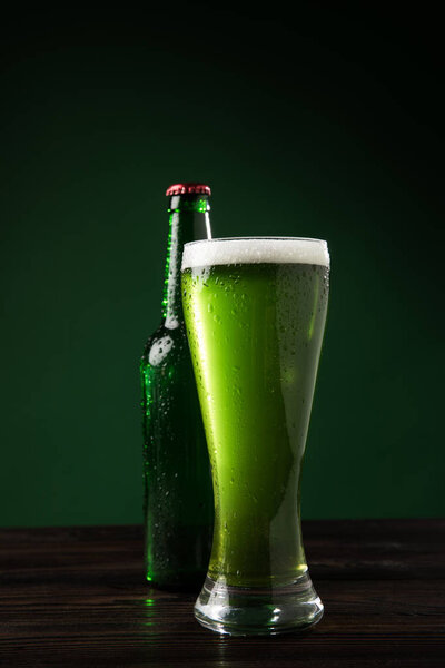 glass bottle and glass of green beer on table, st patricks day concept