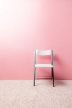 foldable chair in front of pink wall clipart