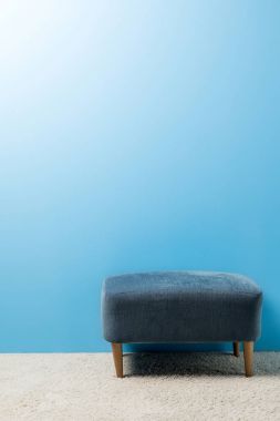 soft hassock standing on carpet in front of blue wall clipart