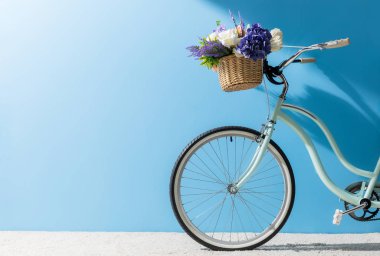 Bisiklet mavi duvar önünde sepette çiçekler ile ön tekerlek