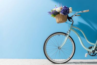 front wheel of bicycle with flowers in basket in front of blue wall clipart