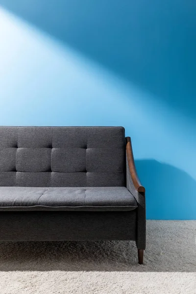 蓝色墙壁前的舒适灰色沙发 — 图库照片
