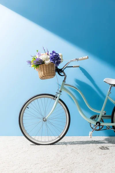 蓝色墙前篮子里有漂亮花朵的自行车 — 图库照片