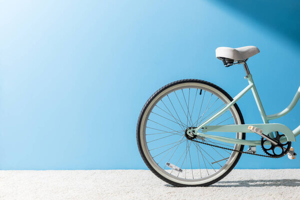 back wheel of bicycle standing on carpet in front of blue wall