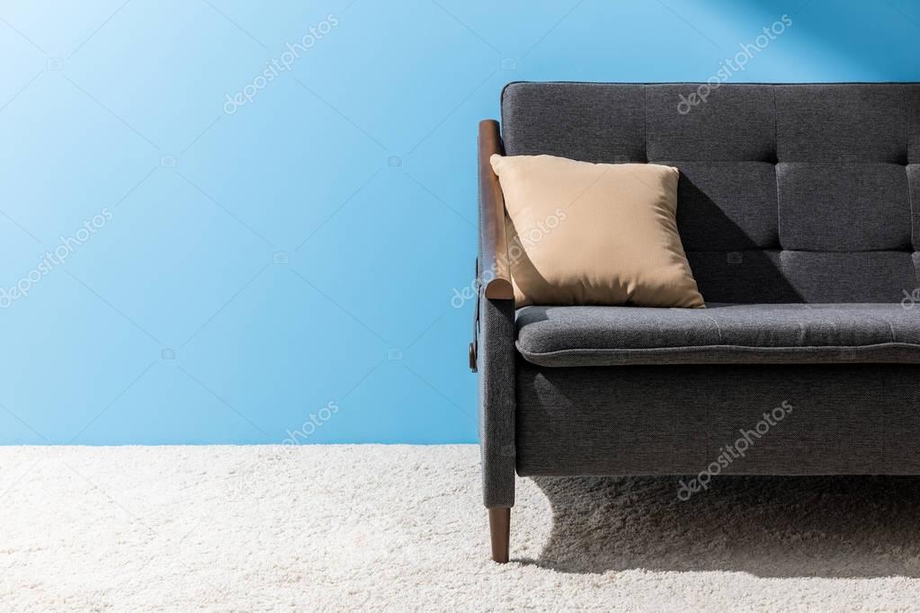 pillow lying on cozy couch in front of blue wall