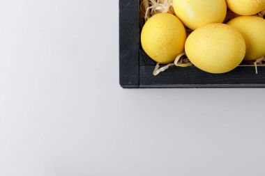 Ahşap kutusunda beyaz izole sarı boyalı Paskalya yumurtaları Üstten Görünüm