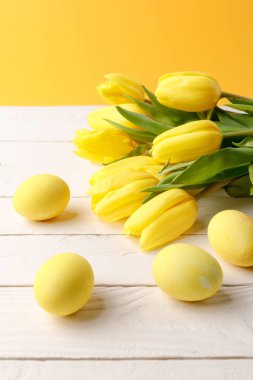 Lale ahşap masa üzerinde buket sarı boyalı Paskalya yumurtaları