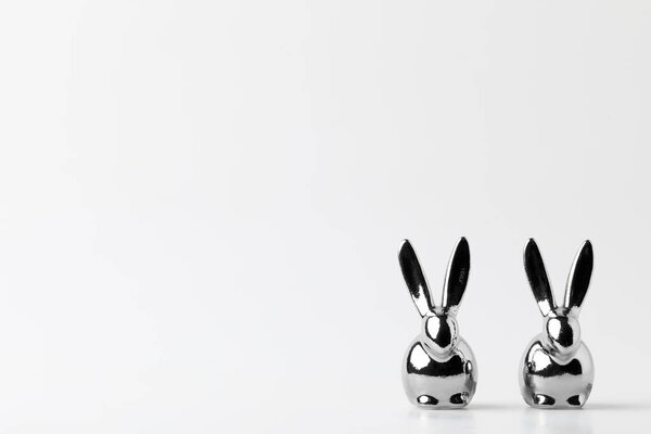 two statuettes of silver easter bunnies on white