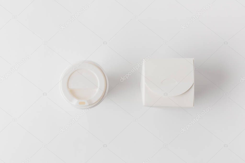 top view of disposable coffee cup and noodles box on white surface