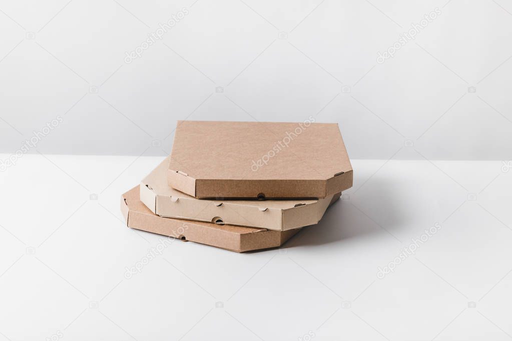 three pizza boxes on white table