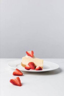 Masada dilimlenmiş çilek tarafından çevreleyen cheesecake ile plaka closeup görünümü