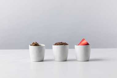 Front view of three bowls with walnuts, grated chocolate and strawberries  clipart