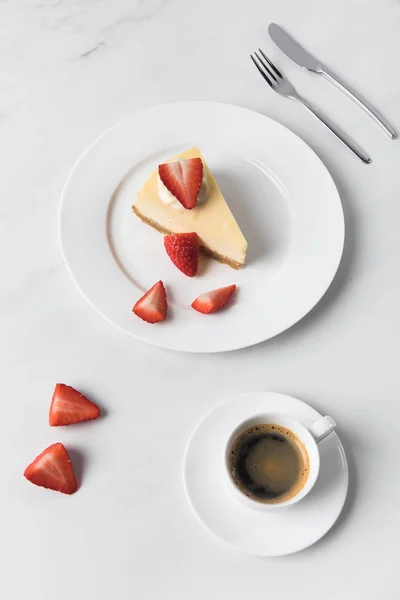 皿にスライスしたイチゴのチーズケーキとコーヒー カップ — ストック写真