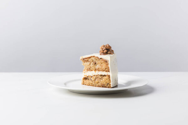 Plate with cake and walnut on top on white surface