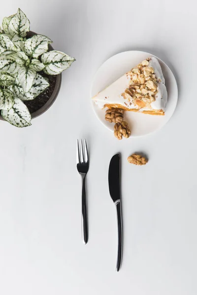 Top view of cake on plate with walnuts and cutlery on grey