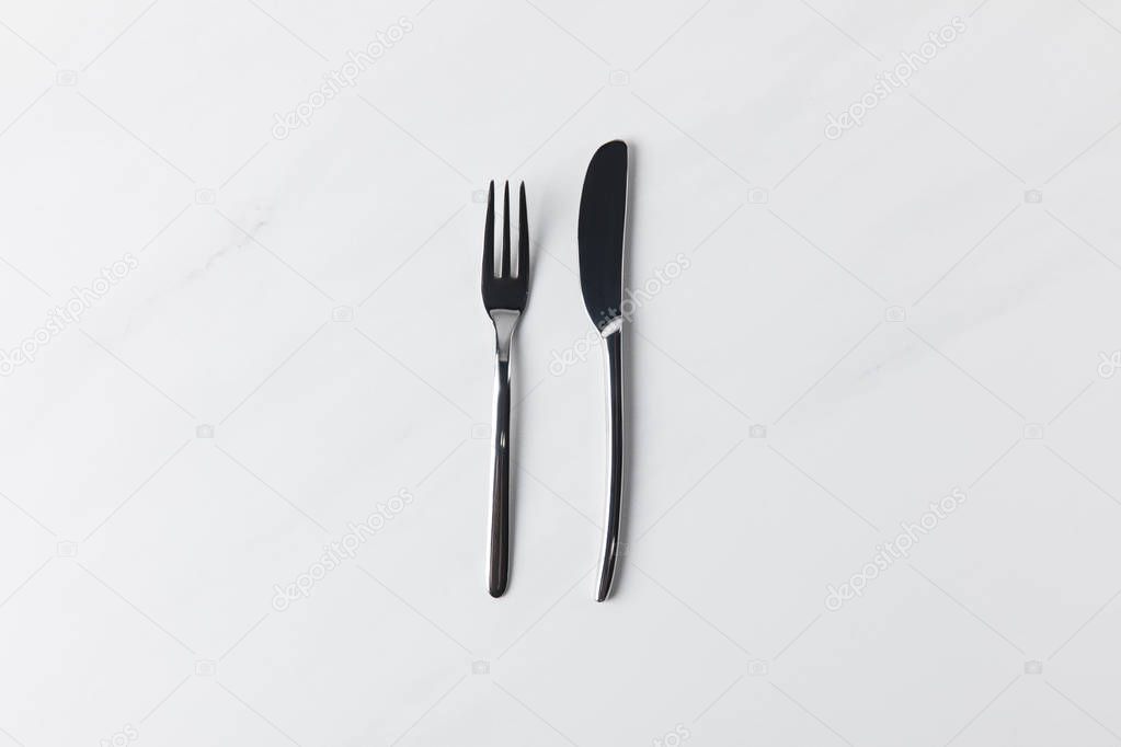 Fork and knife placed on white surface, table appointments conception