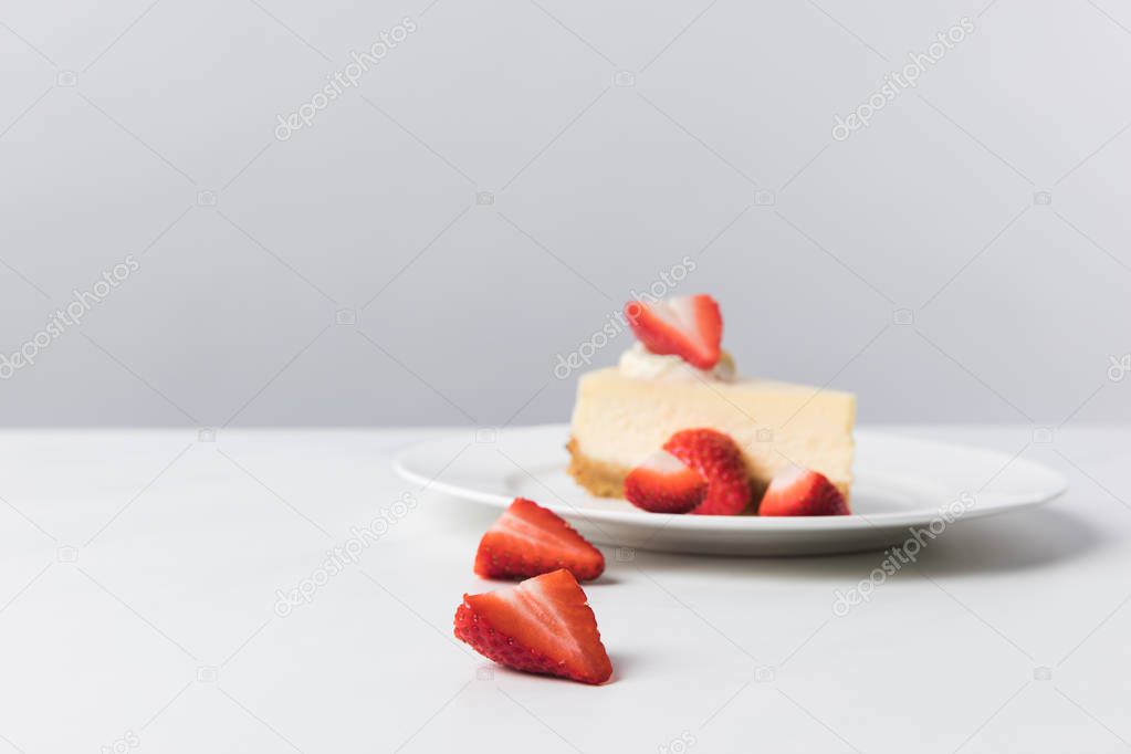 Plate with cheesecake surrounding by fresh sliced strawberries