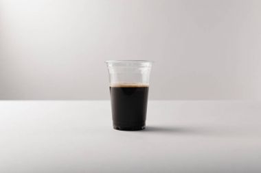 Beyaz arka planda siyah kahve ile plastik bardak