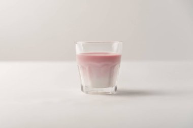 Süt beyaz arka plan üzerinde pembe şurubu ile cam