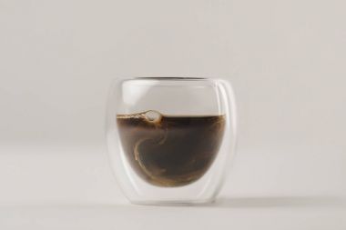 Swirls of milk in Double Walled Glass with coffee on white background clipart