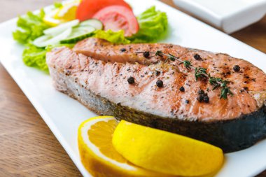 close-up view of delicious grilled salmon with lemon slices and vegetable salad clipart