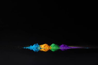 four colors of holi powder for Hindu spring festival, on black with reflection clipart