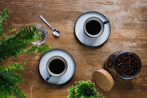 Morning black coffee in cups on table with plants in coffee shop