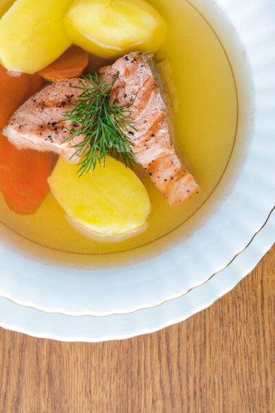 top view of delicious healthy salmon soup on wooden tabletop 