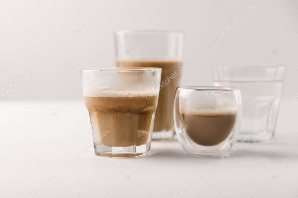 Glasses with coffee and milk on white background