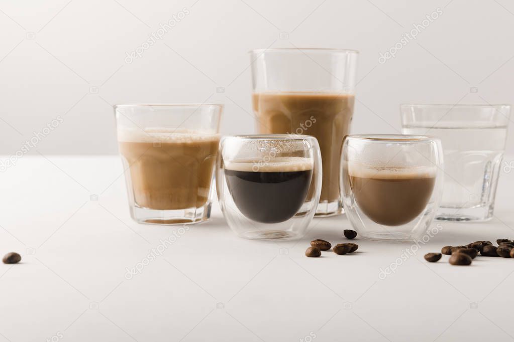 Set of cups with assorted coffee drinks on white background