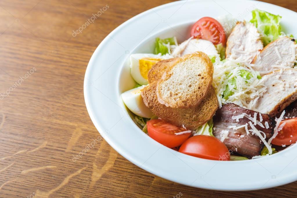 close-up view of gourmet caesar salad on wooden table
