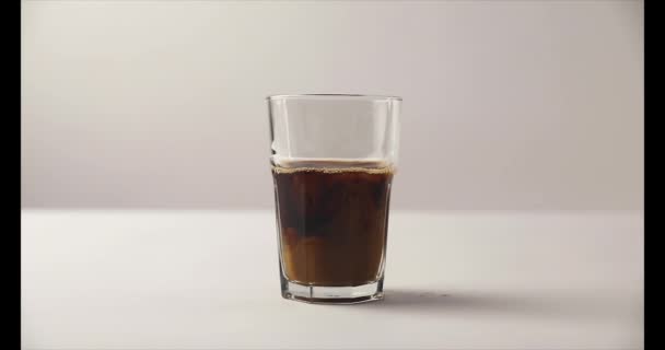 Zpomalený pohyb nalévání mléka v staré tvarovaného skla s kávou na bílém pozadí