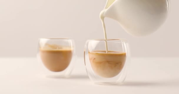 Wlewając Mleko Dzbanek Jednym Dwóch Filiżanek Kawą Białym Tle — Wideo stockowe