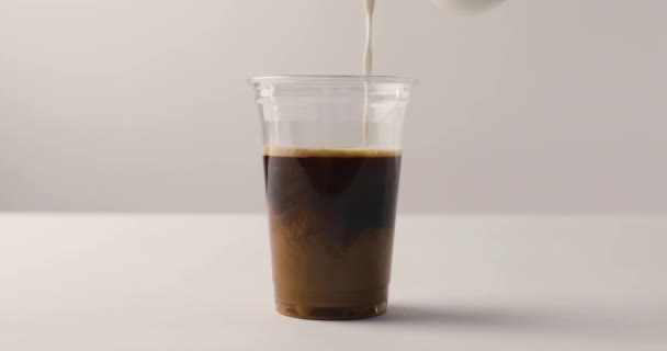 Műanyag pohár kávét tej ömlött a fehér háttér, fordított felvételeket