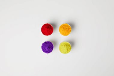top view of four colors of holi powder in bowls on white, Hindu spring festival clipart