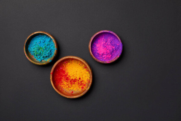 top view of colorful holi powder in bowls on grey surface 