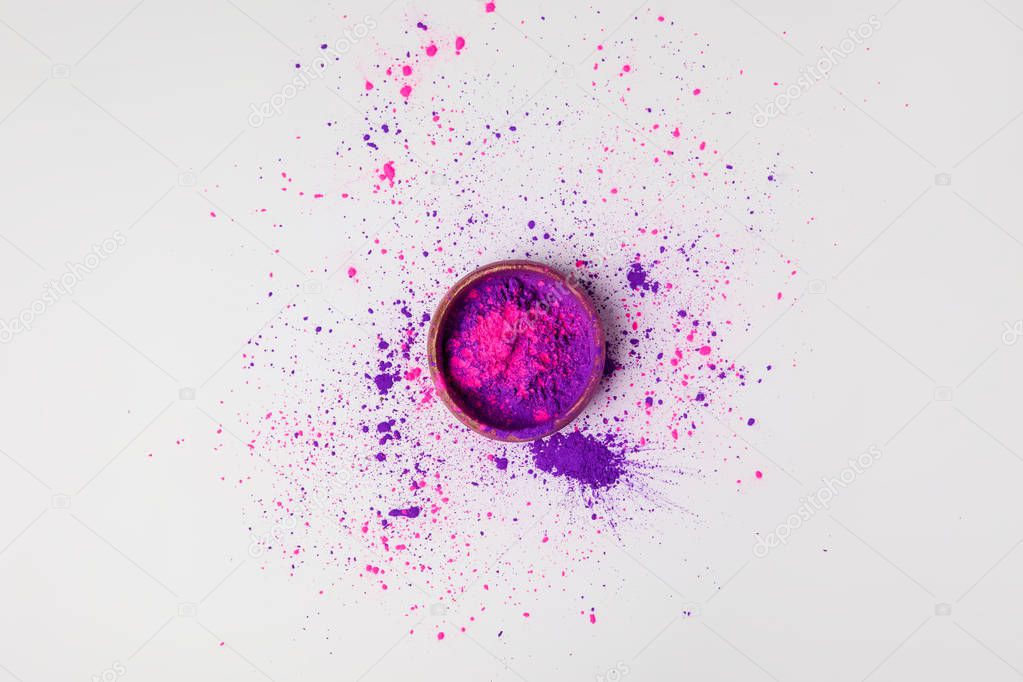top view of purple and pink holi powder in bowl isolated on white