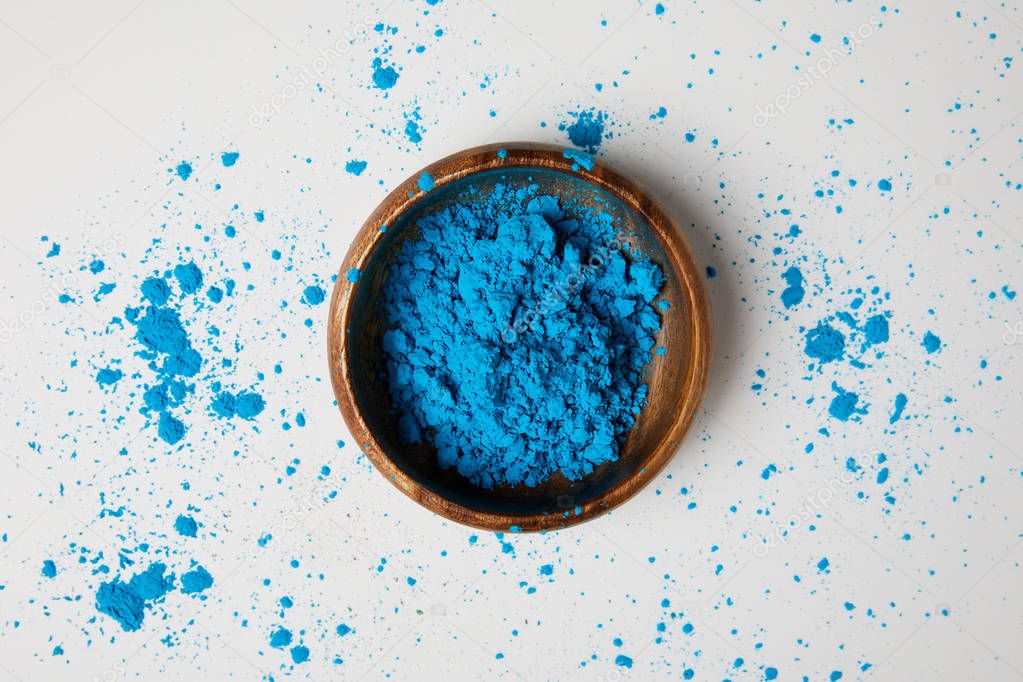 top view of blue holi paint in bowl isolated on white, Hindu spring festival