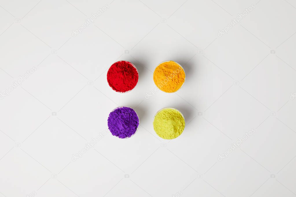 top view of four colors of holi powder in bowls on white, Hindu spring festival