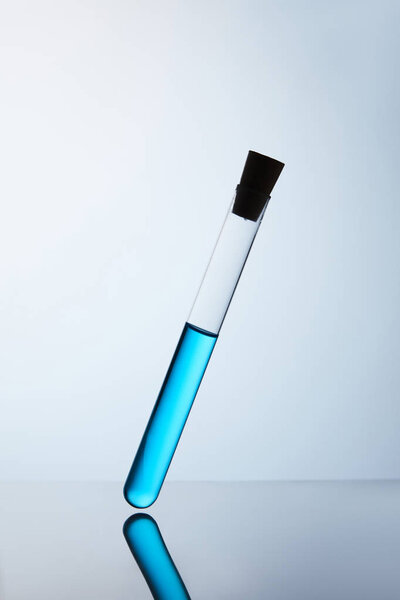 chemistry tube filled with blue liquid on reflective surface