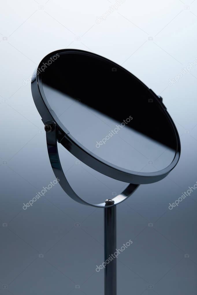close-up shot of cosmetic mirror with stand on grey