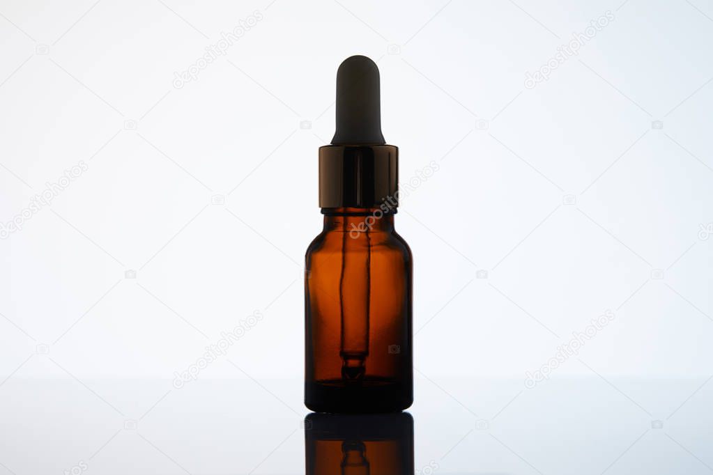 close-up shot of bottle of aromatic oil with pipette on reflective surface