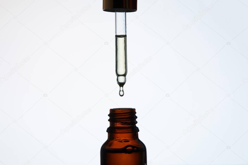 close-up shot of bottle of aromatic oil with pipette above on white